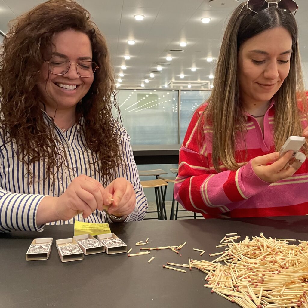 Two workshop participants playing a serious game with matchsticks during a Gnist team dynamics session.