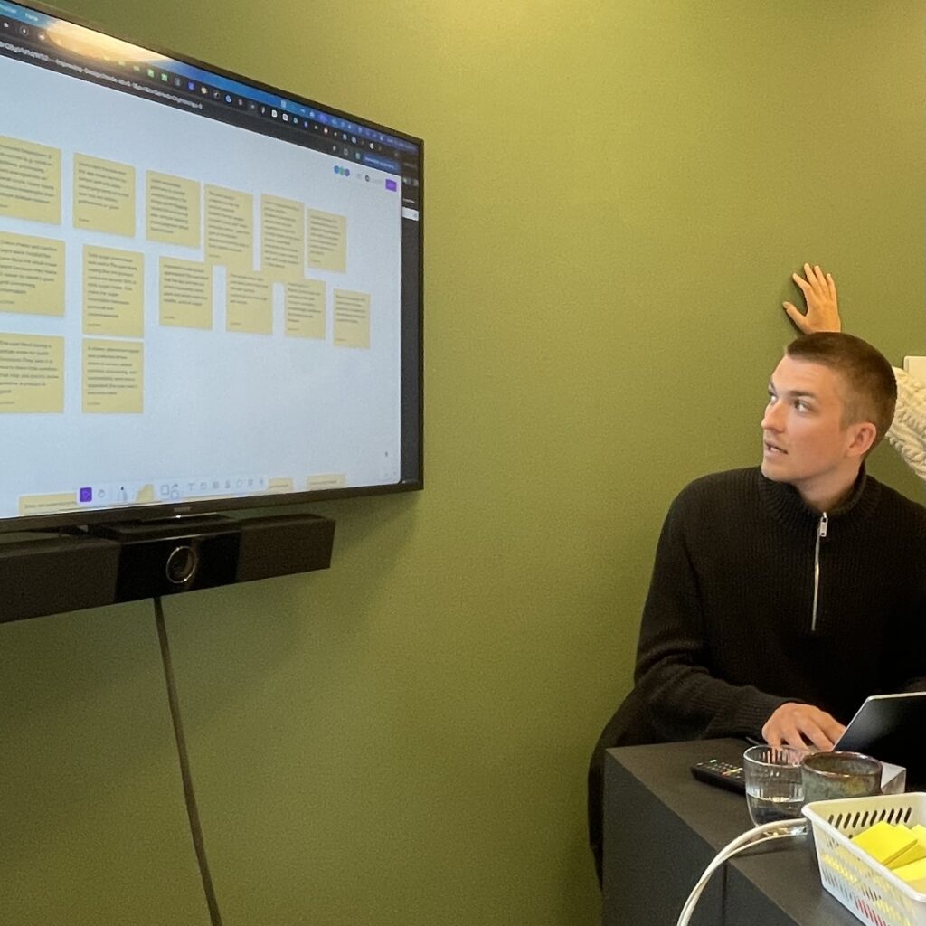 Workshop participant in a problem definition session with virtual sticky notes on a screen.